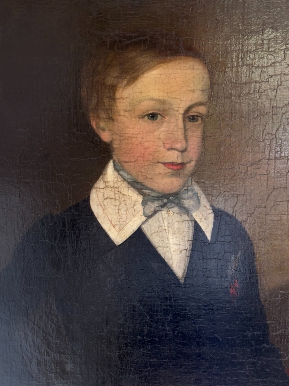 An antique oil portrait depicting a young male scholar in a dark blue coat and white collar, set in a gilded ornate frame. View III