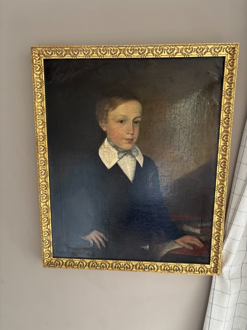 An antique oil portrait depicting a young male scholar in a dark blue coat and white collar, set in a gilded ornate frame.