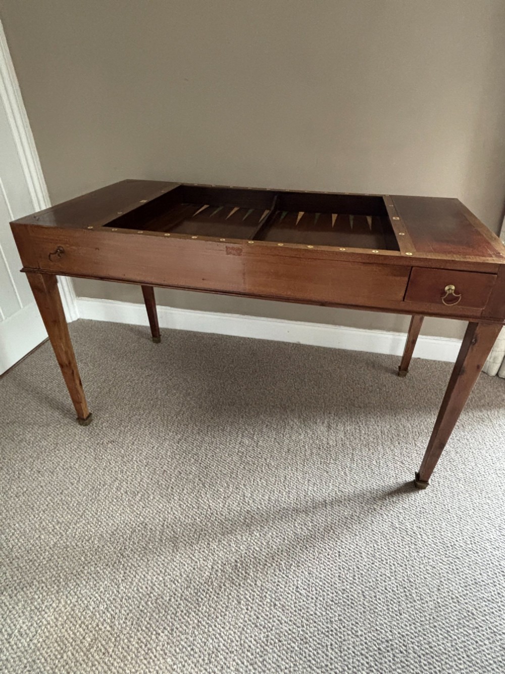 A French Empire mahogany tric-trac games table featuring a sunken central backgammon board with inlaid points and brass eyelets around the border. View V