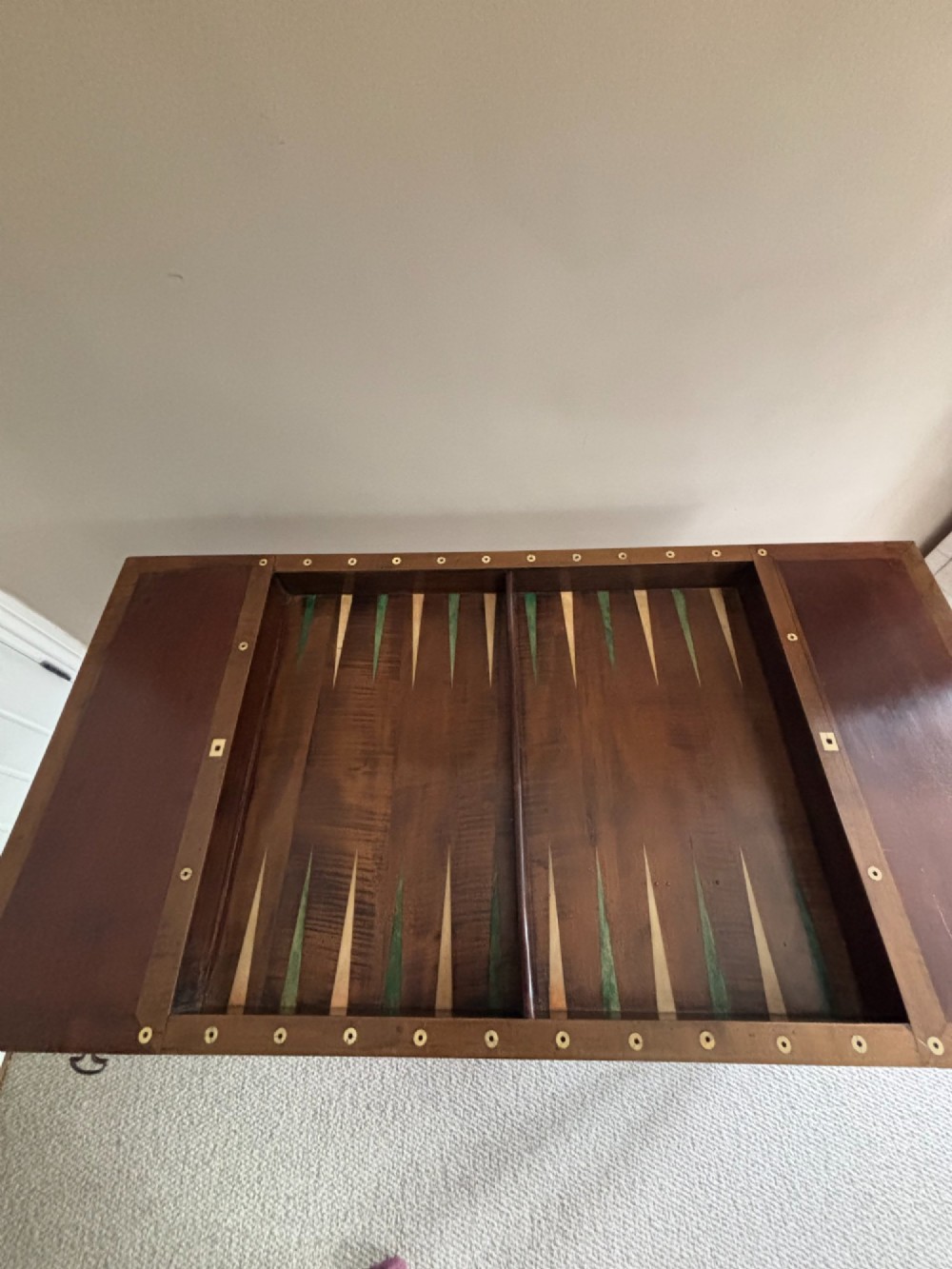 A French Empire mahogany tric-trac games table featuring a sunken central backgammon board with inlaid points and brass eyelets around the border. View VI