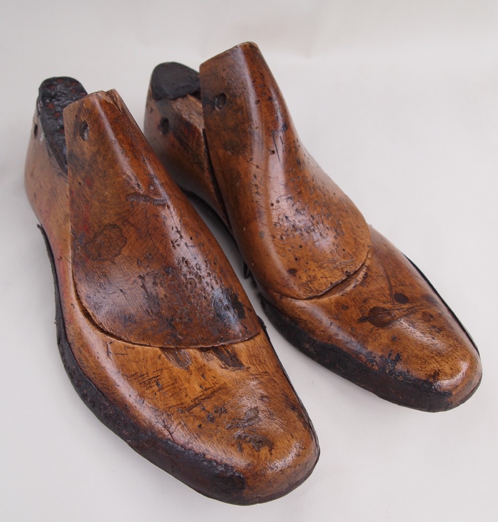 A pair of late 19th-century carved beechwood gents shoe lasts with a warm brown patinated finish and visible cobbler pin marks.