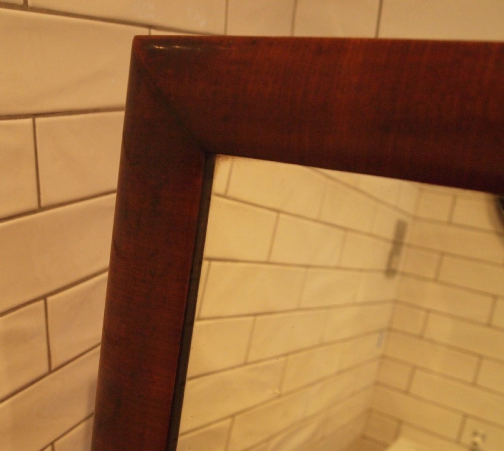 A Victorian mahogany cheval mirror featuring a rectangular pivoting frame supported by turned side uprights with adjustment knobs and carved scroll feet. View IV
