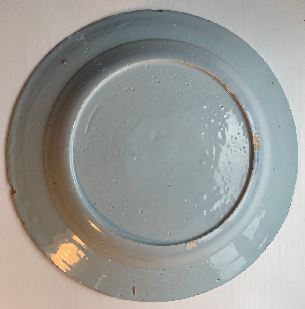 An 18th-century tin-glazed earthenware plate featuring hand-painted cobalt blue chinoiserie floral motifs on a pale blue-white ground. View II