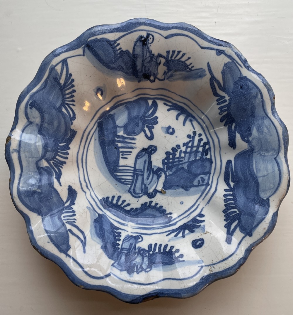 An eighteenth-century Dutch Delftware lobed ceramic bowl featuring hand-painted cobalt blue chinoiserie imagery on a white tin-glazed background.