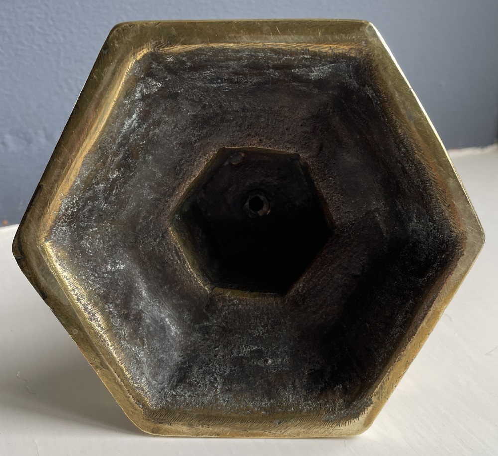 A cast brass candlestick featuring a turned knopped stem, engraved leaf details, a circular drip tray, and a stepped octagonal base. View IV