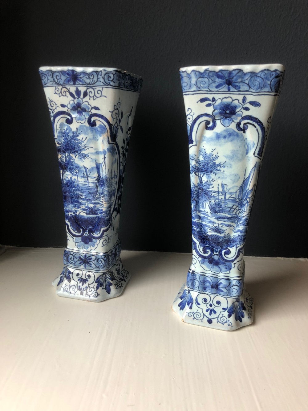 A pair of early nineteenth-century French faience posy vases featuring hand-painted blue maritime vignettes and floral scrollwork on a white background.