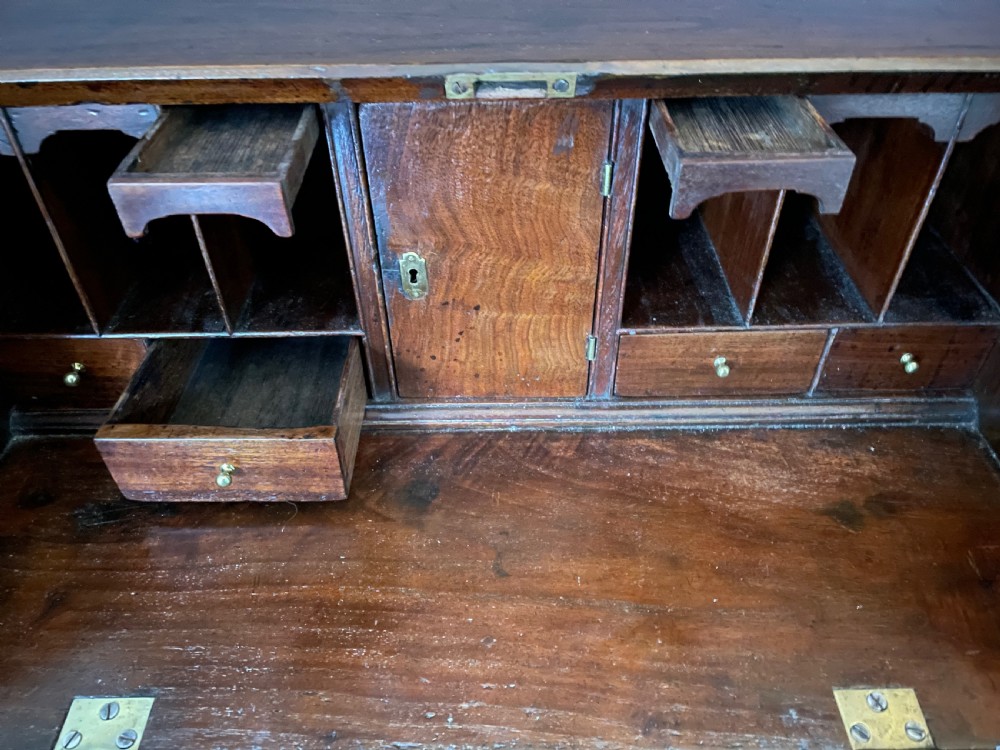An 18th-century George II elm bureau featuring a slanted fall-front flap above four drawers with brass handles and bracket feet. View III