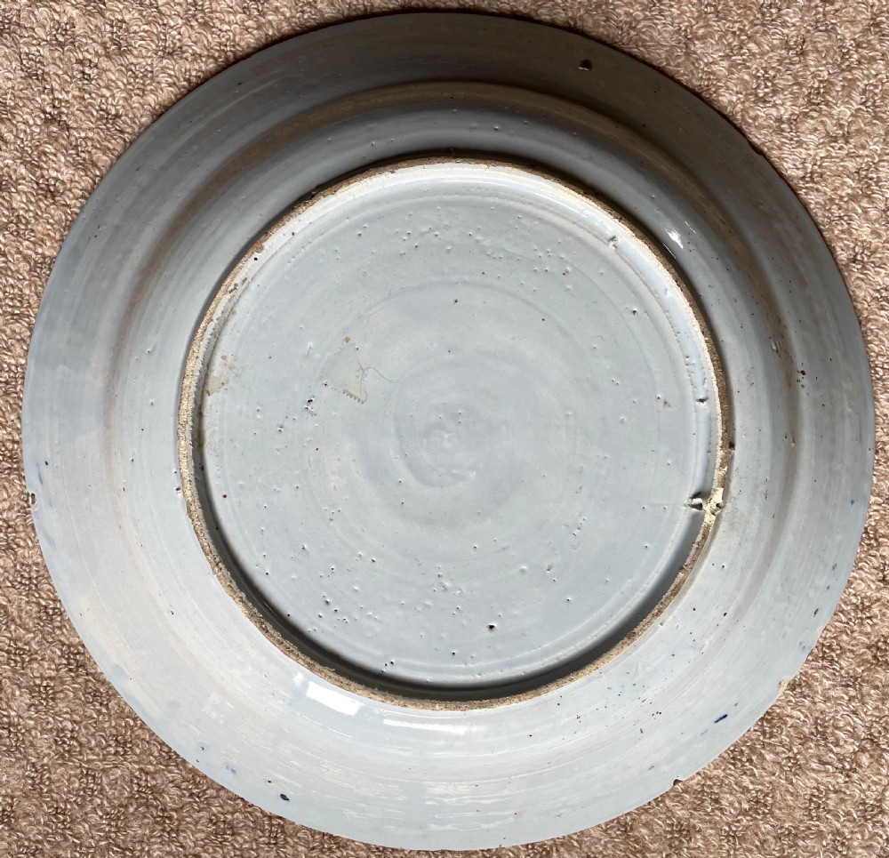 An eighteenth-century circular English delftware charger hand-painted with cobalt blue chinoiserie landscape motifs on a tin-glazed white surface. View III