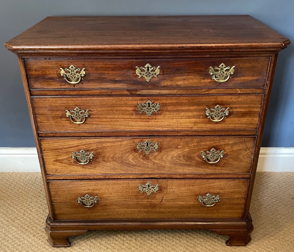 A small 19th-century wooden chest of drawers featuring four graduated drawers with pierced brass handles and bracket feet. View II