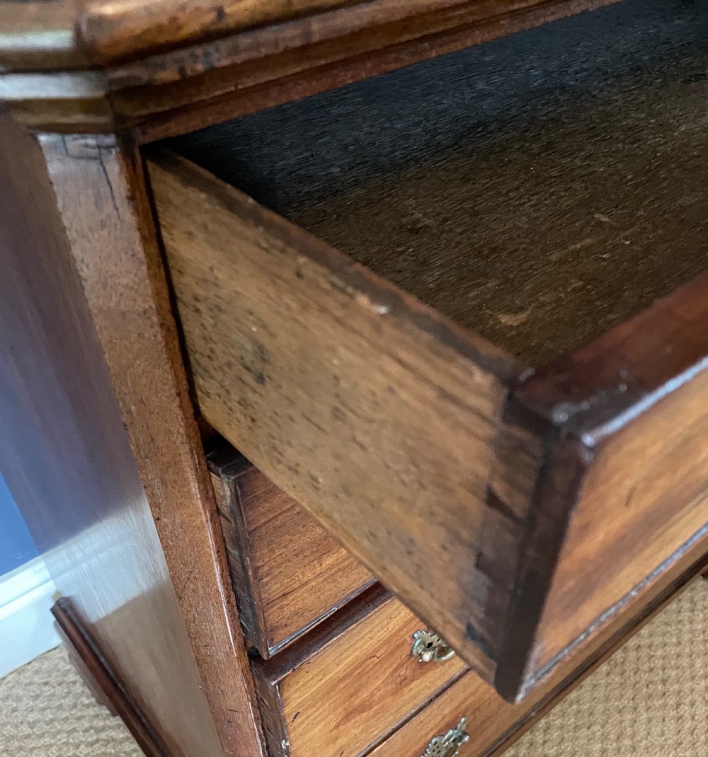 A small 19th-century wooden chest of drawers featuring four graduated drawers with pierced brass handles and bracket feet. View III