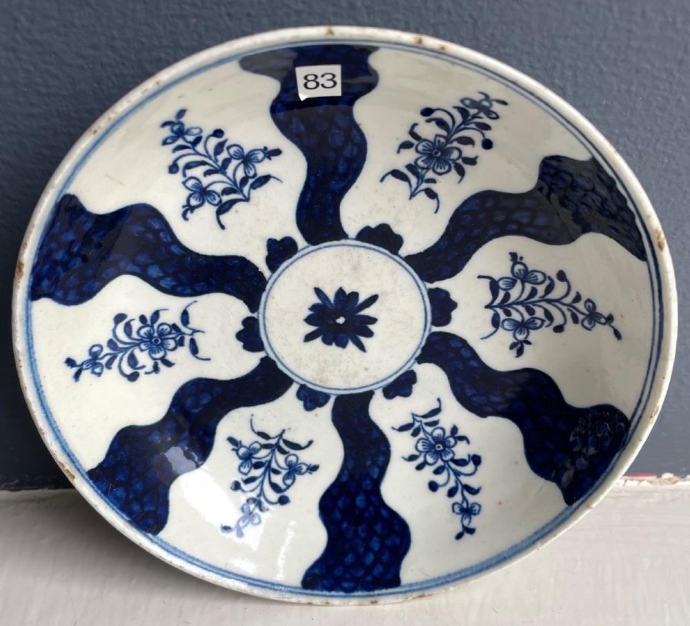 An 18th-century Lowestoft soft-paste porcelain tea bowl and saucer set decorated in underglaze cobalt blue with wavy bands and floral sprays. View II