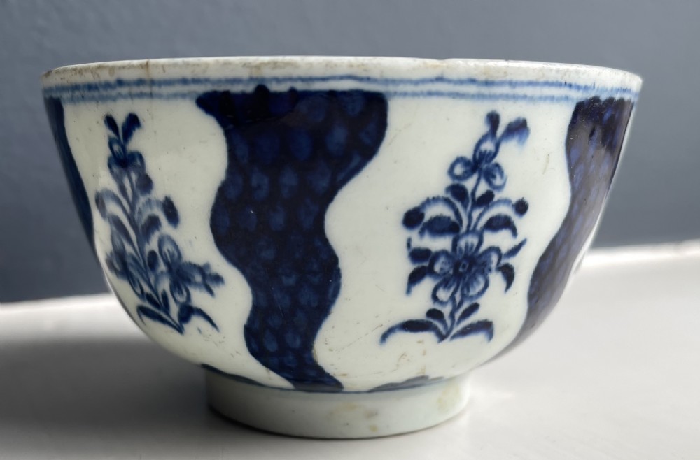 An 18th-century Lowestoft soft-paste porcelain tea bowl and saucer set decorated in underglaze cobalt blue with wavy bands and floral sprays. View III