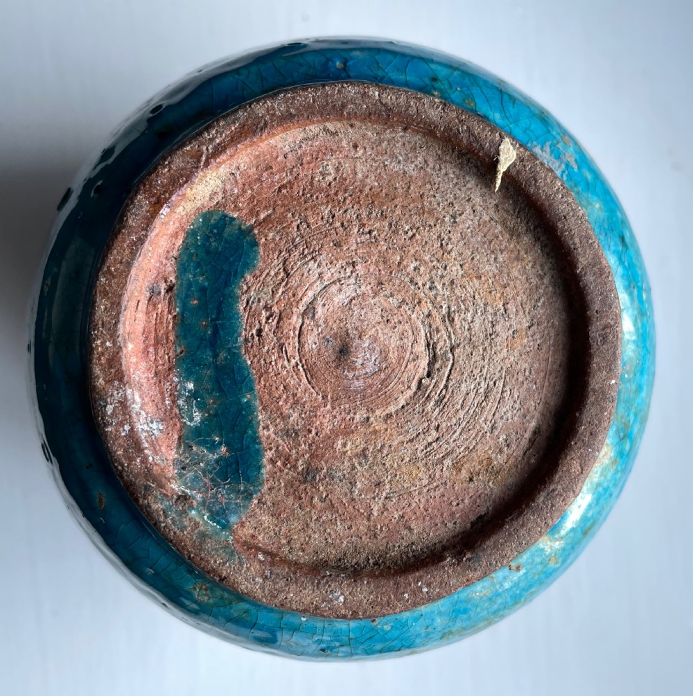 A turquoise glazed ceramic vessel with a flared rim, painted black geometric markings, and fine surface craquelure. View III