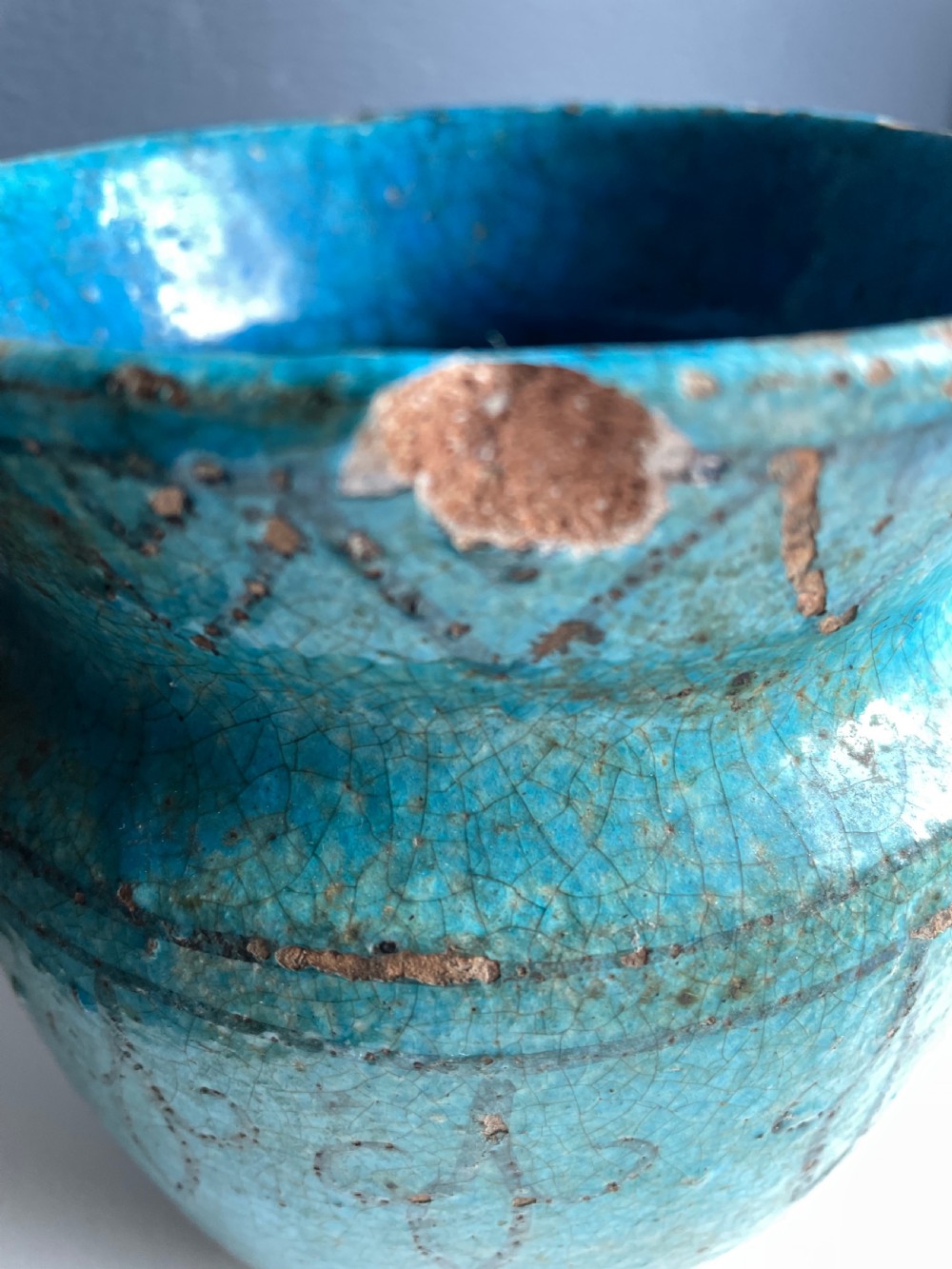 A turquoise glazed ceramic vessel with a flared rim, painted black geometric markings, and fine surface craquelure. View IV
