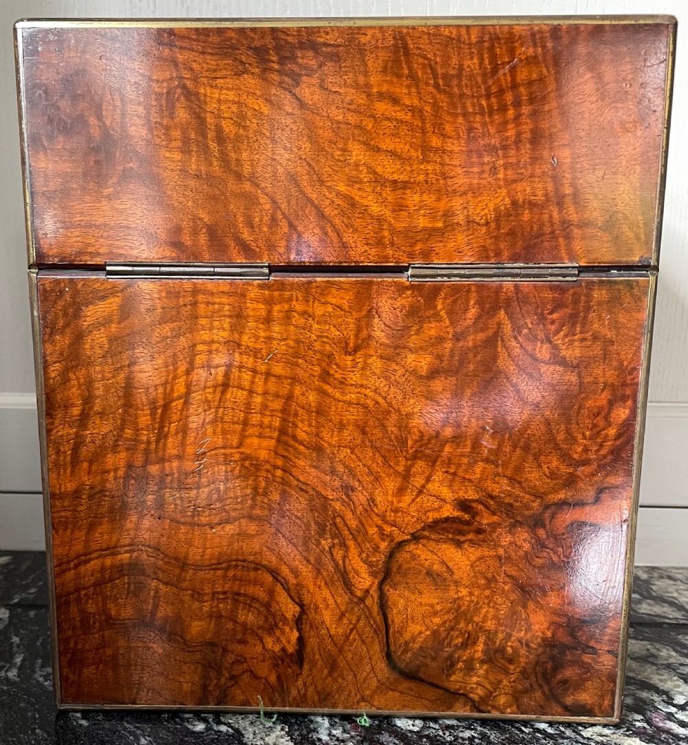 A closed rectangular burr walnut decanter box featuring thin brass trim around the outer edges and a circular brass keyhole escutcheon. View VI