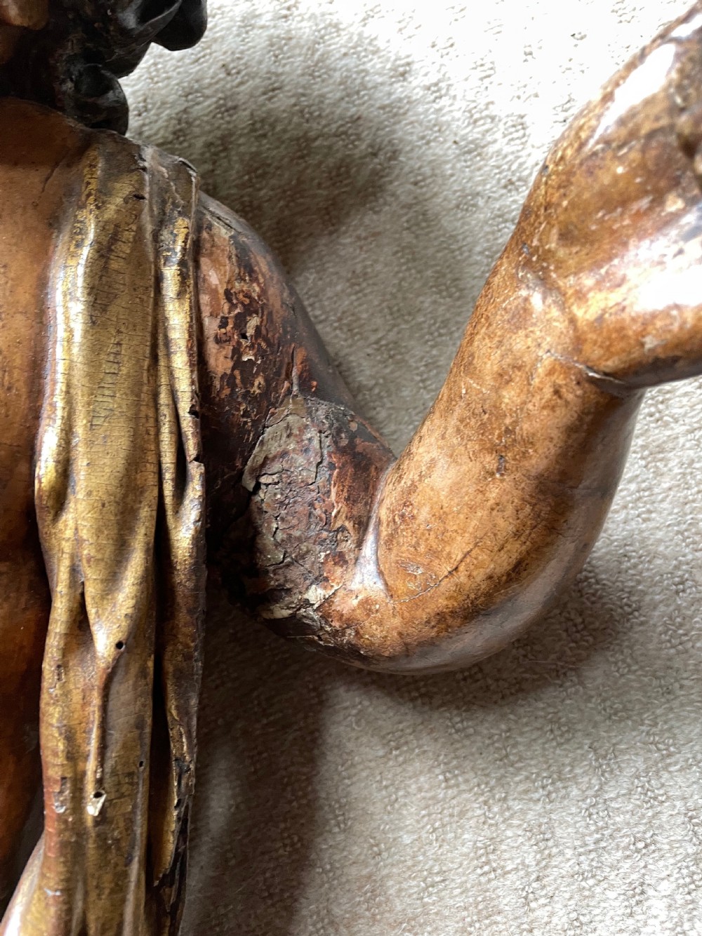 A pair of 17th-century French carved limewood putti featuring curly hair, draped sashes, and dynamic seated poses with a warm aged surface patina. View V