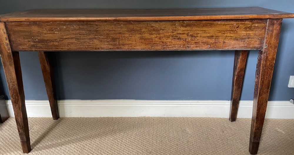 A nineteenth-century Chinese elm side table featuring three drawers with brass drop handles and straight legs set against a dark blue wall. View IV
