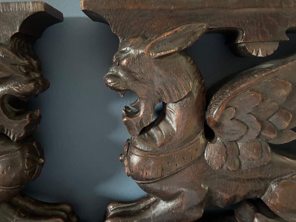 A facing pair of 19th-century carved dark oak panels depicting winged griffins set within rectangular timber frames. View II