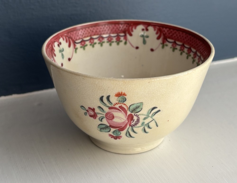 An 18th-century creamware tea bowl decorated with hand-painted floral motifs and an ornate pink interior border. View III