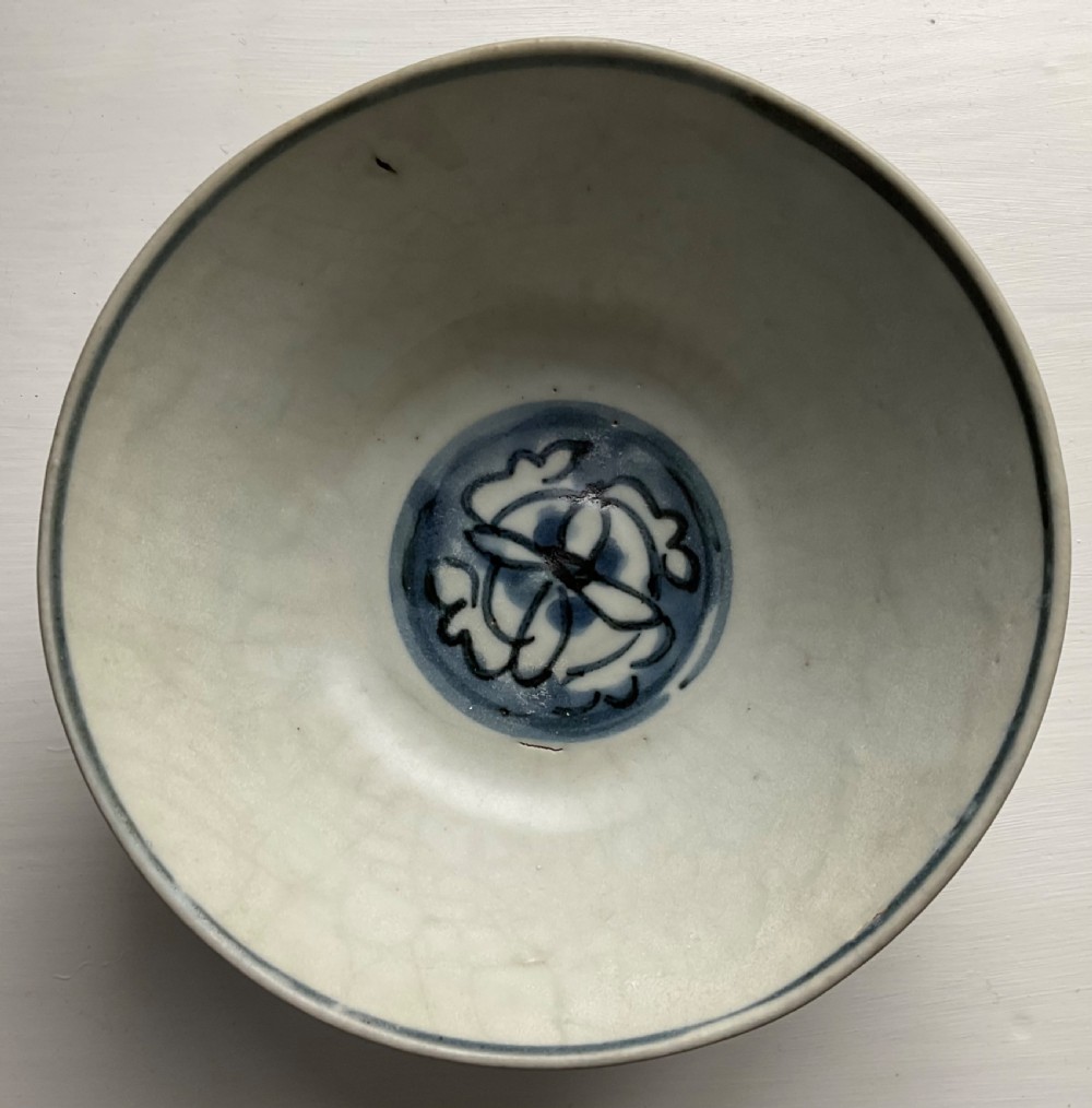 A circular blue and white ceramic bowl painted with underglaze cobalt floral motifs resting on an unglazed raised foot rim. View III