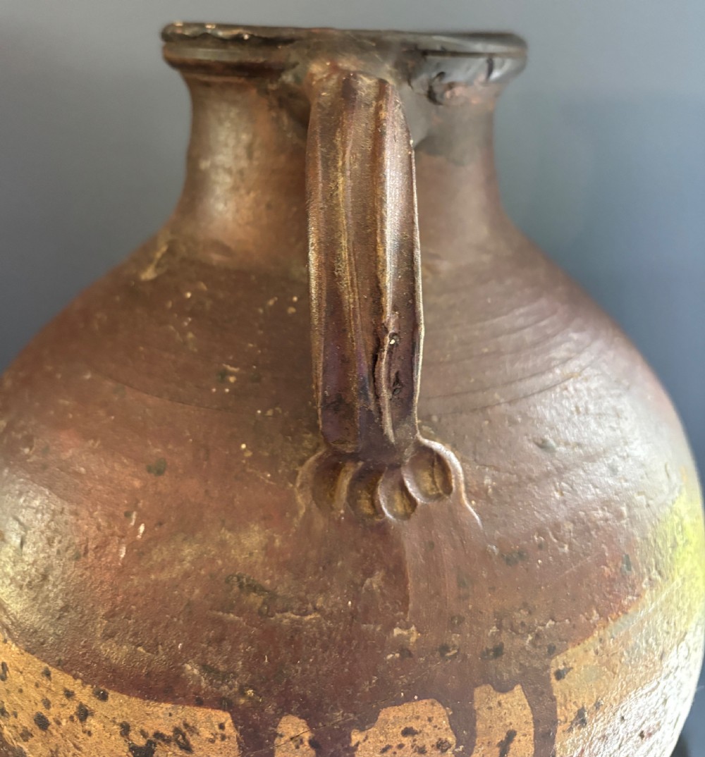 A large 17th-century earthenware tavern jug featuring a rounded body, piecrust footed rim, strap handle, and faded slip decoration. View III
