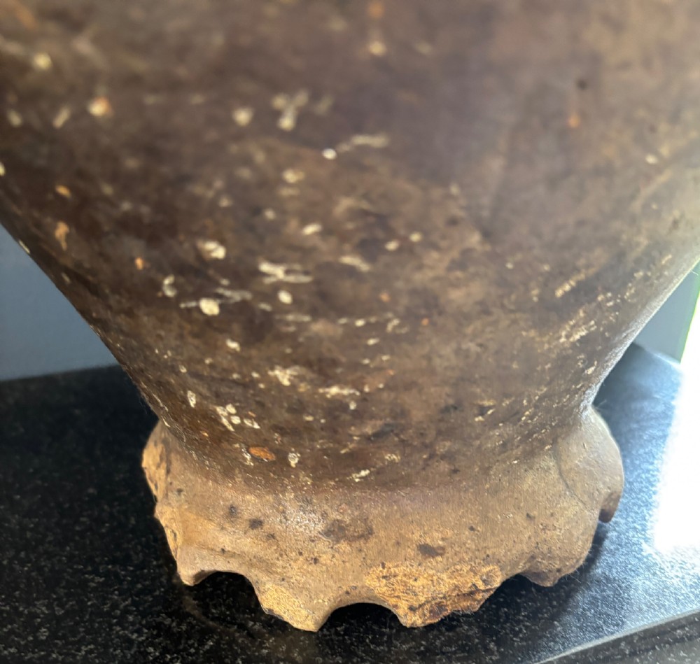 A large 17th-century earthenware tavern jug featuring a rounded body, piecrust footed rim, strap handle, and faded slip decoration. View IV