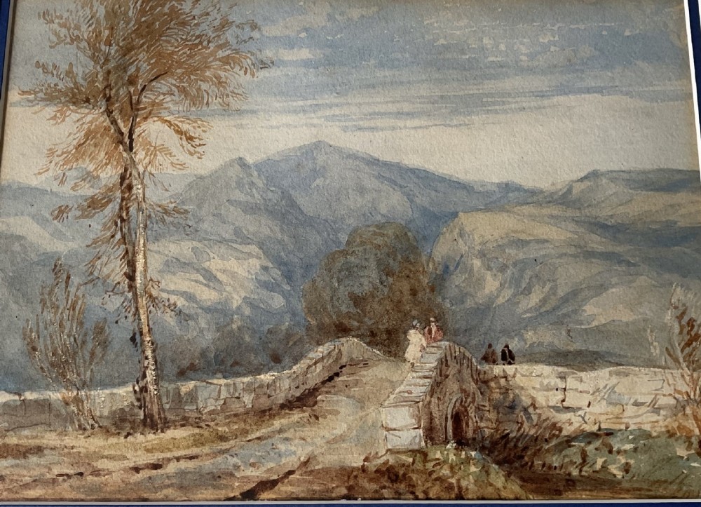 A 19th-century watercolour landscape painting depicting figures standing on a stone arch bridge with mountains in the background and a leafless tree on the left.
