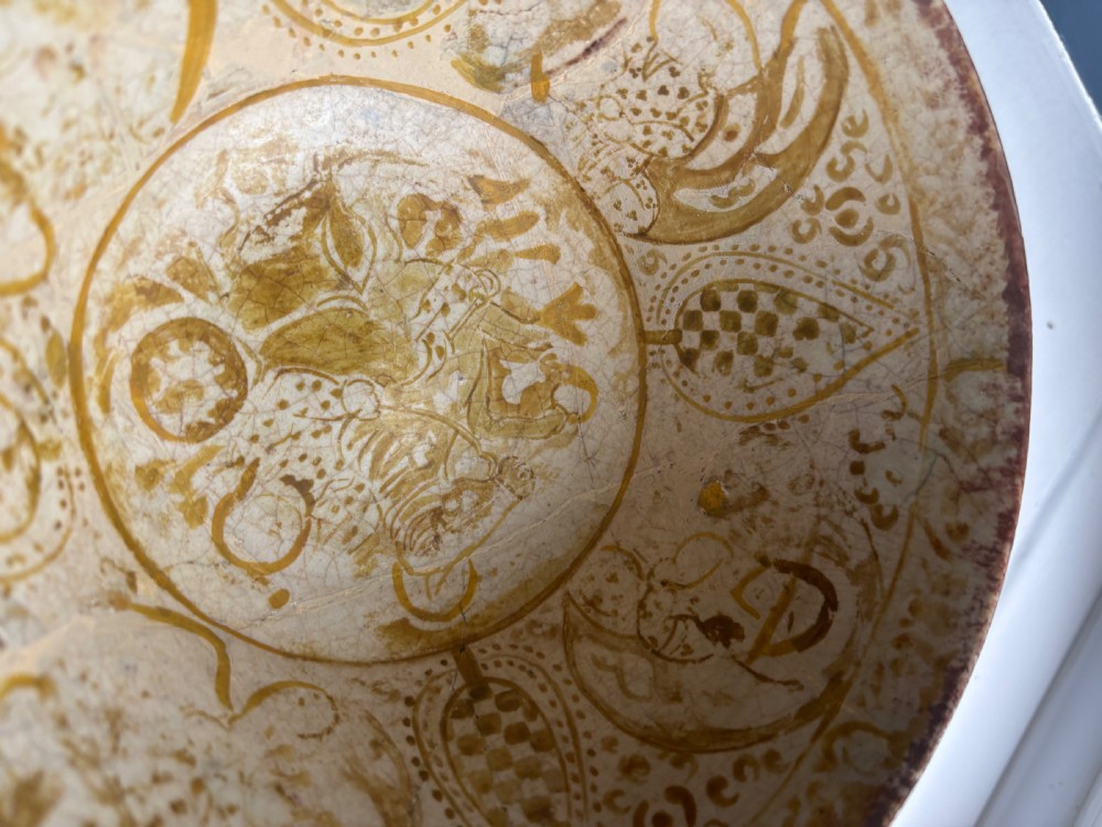 A round antique Persian ceramic footed bowl featuring golden-ochre lustre painted motifs and geometric borders on a craquelure off-white glaze. View VI