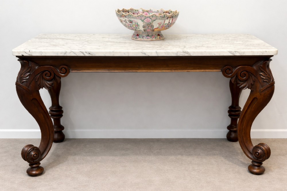 A late 19th-century console table featuring a white marble top supported by carved dark wood S-scroll legs.