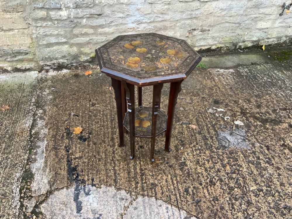 An octagonal dark wood Arts and Crafts occasional table featuring hand-painted fruit motifs on the top surface and lower tier.