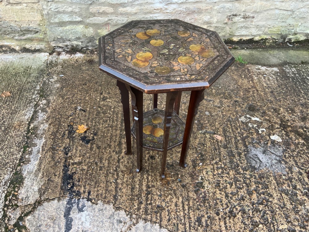 An octagonal dark wood Arts and Crafts occasional table featuring hand-painted fruit motifs on the top surface and lower tier. View V