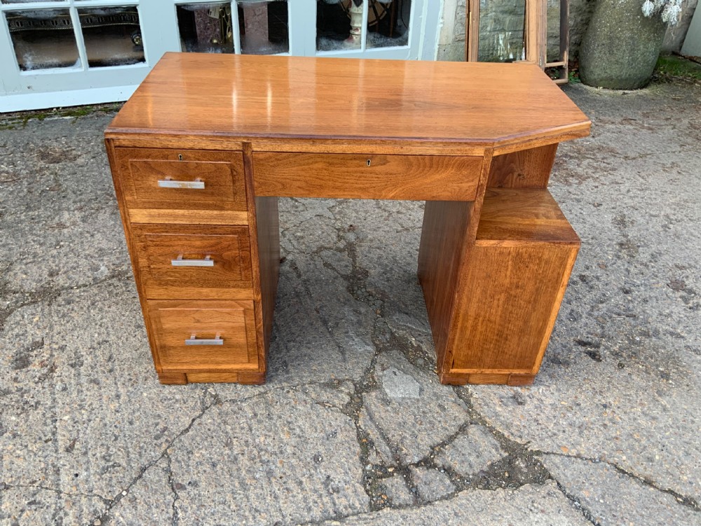 An Art Deco walnut desk featuring a left-hand pedestal of three drawers, a central kneehole drawer, an asymmetric stepped side tier, and metallic bar handles.