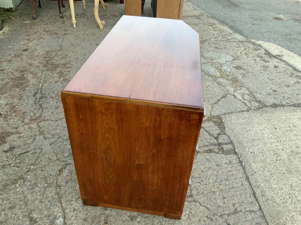 An Art Deco walnut desk featuring a left-hand pedestal of three drawers, a central kneehole drawer, an asymmetric stepped side tier, and metallic bar handles. View II