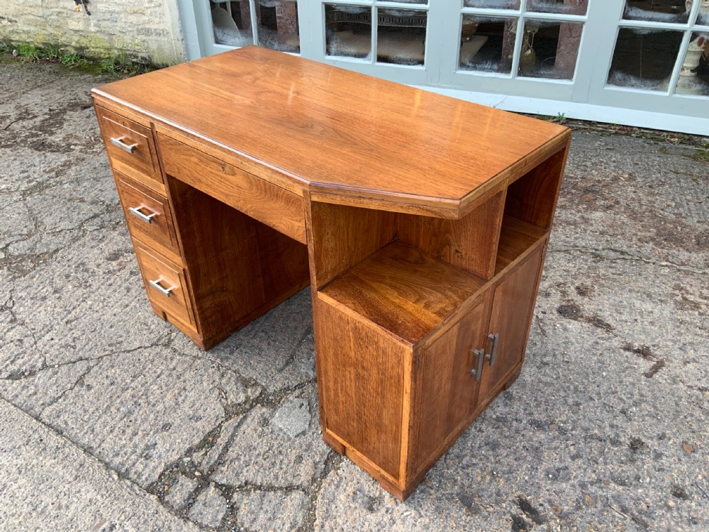 An Art Deco walnut desk featuring a left-hand pedestal of three drawers, a central kneehole drawer, an asymmetric stepped side tier, and metallic bar handles. View III