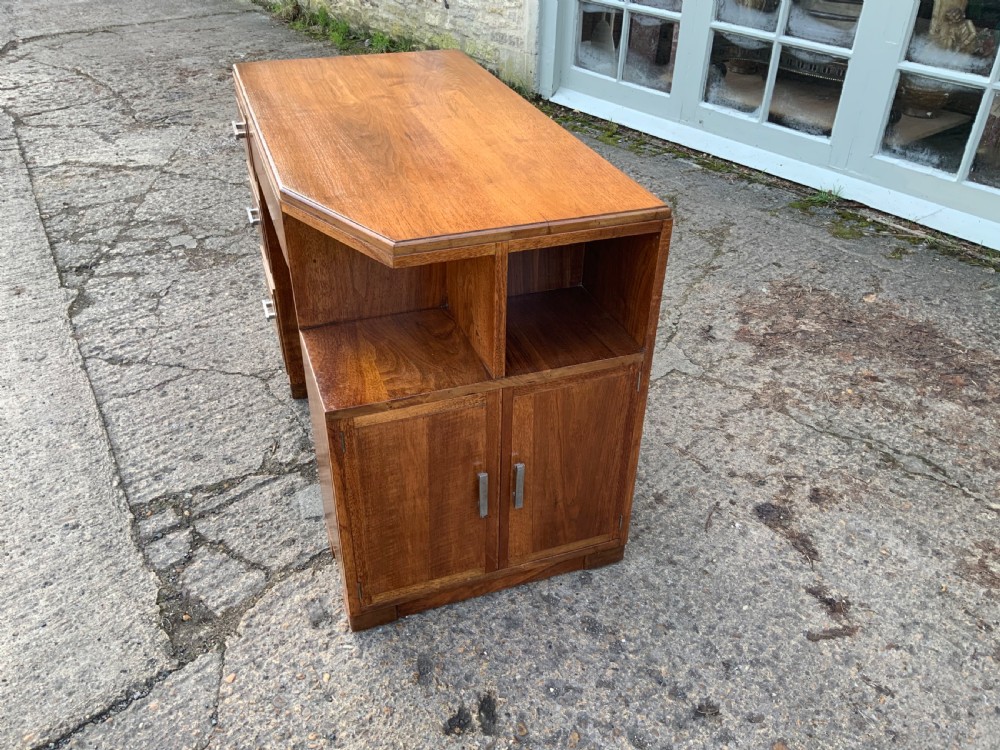 An Art Deco walnut desk featuring a left-hand pedestal of three drawers, a central kneehole drawer, an asymmetric stepped side tier, and metallic bar handles. View V