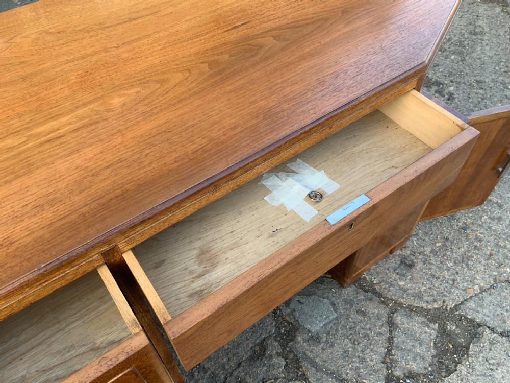 An Art Deco walnut desk featuring a left-hand pedestal of three drawers, a central kneehole drawer, an asymmetric stepped side tier, and metallic bar handles. View IX