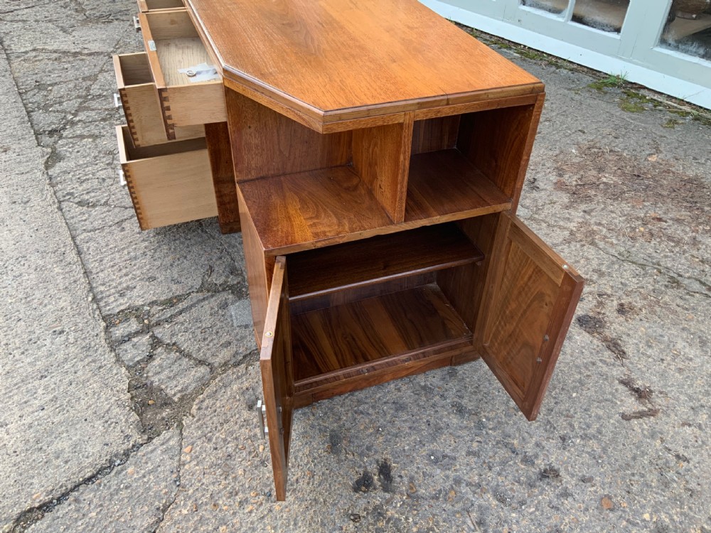 An Art Deco walnut desk featuring a left-hand pedestal of three drawers, a central kneehole drawer, an asymmetric stepped side tier, and metallic bar handles. View X