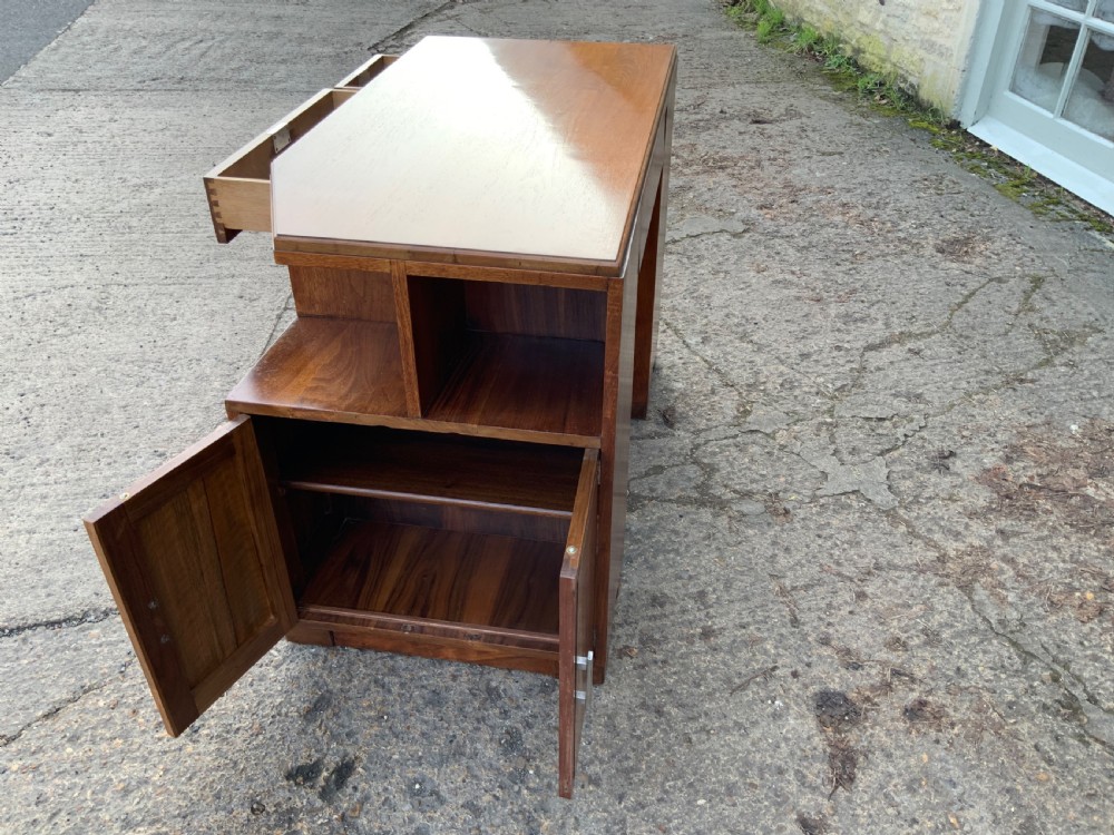 An Art Deco walnut desk featuring a left-hand pedestal of three drawers, a central kneehole drawer, an asymmetric stepped side tier, and metallic bar handles. View XI