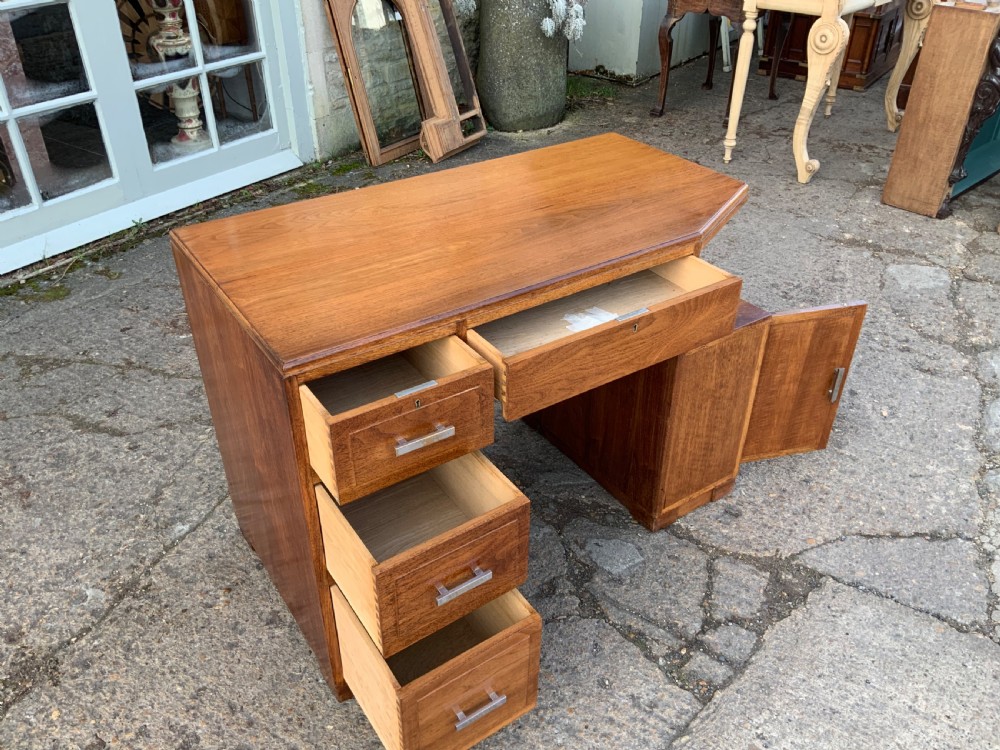 An Art Deco walnut desk featuring a left-hand pedestal of three drawers, a central kneehole drawer, an asymmetric stepped side tier, and metallic bar handles. View XII