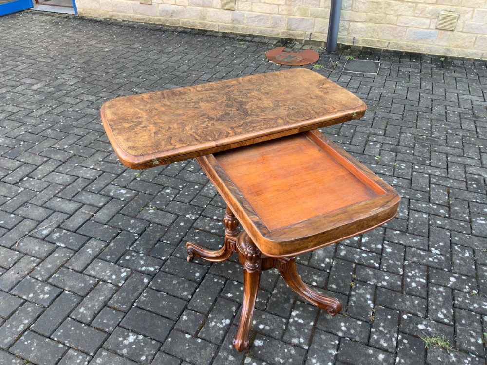 A Victorian burr walnut fold-top card table with highly figured wood grain, turned column supports, a central finial, and four carved splayed legs. View VII