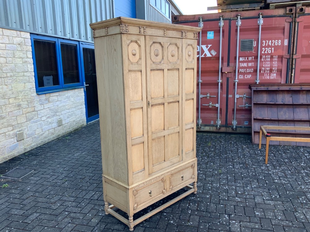 A light oak double wardrobe featuring geometric panelled doors, octagonal raised bosses, two base drawers, and turned legs. View II