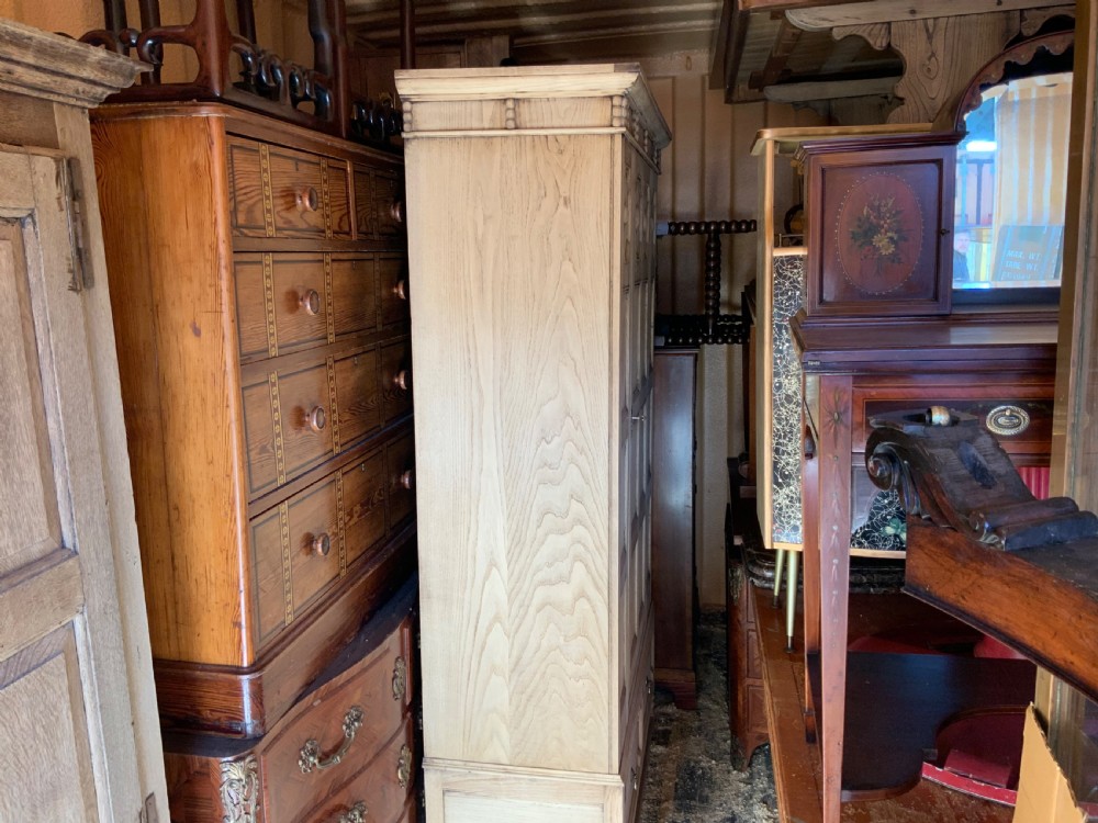 A light oak double wardrobe featuring geometric panelled doors, octagonal raised bosses, two base drawers, and turned legs. View VI
