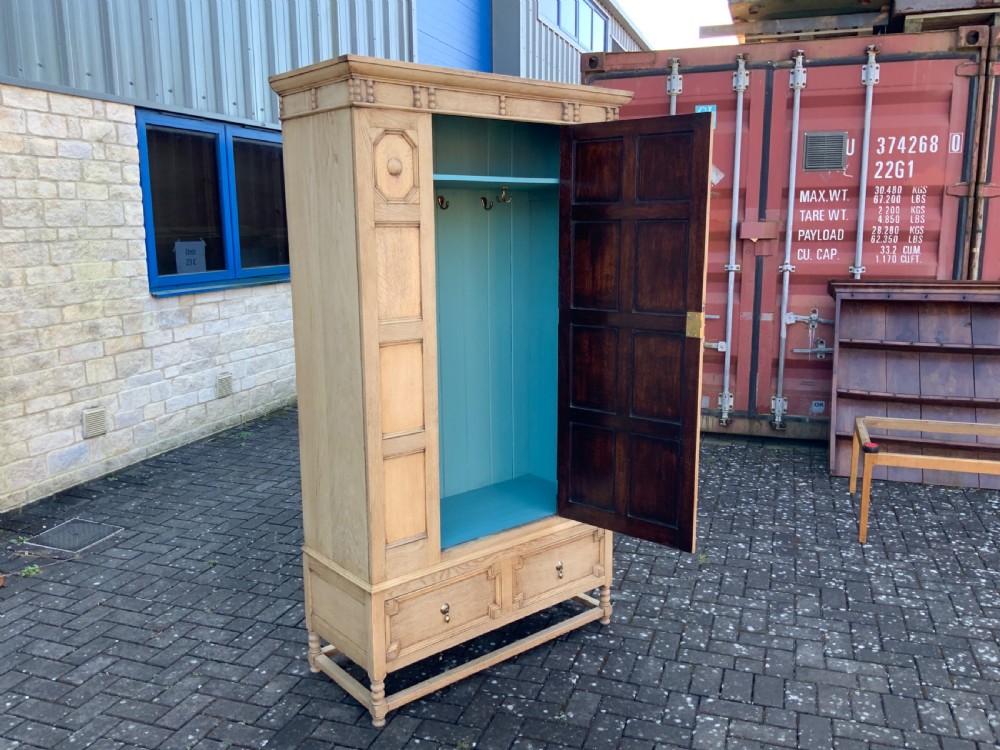A light oak double wardrobe featuring geometric panelled doors, octagonal raised bosses, two base drawers, and turned legs. View X