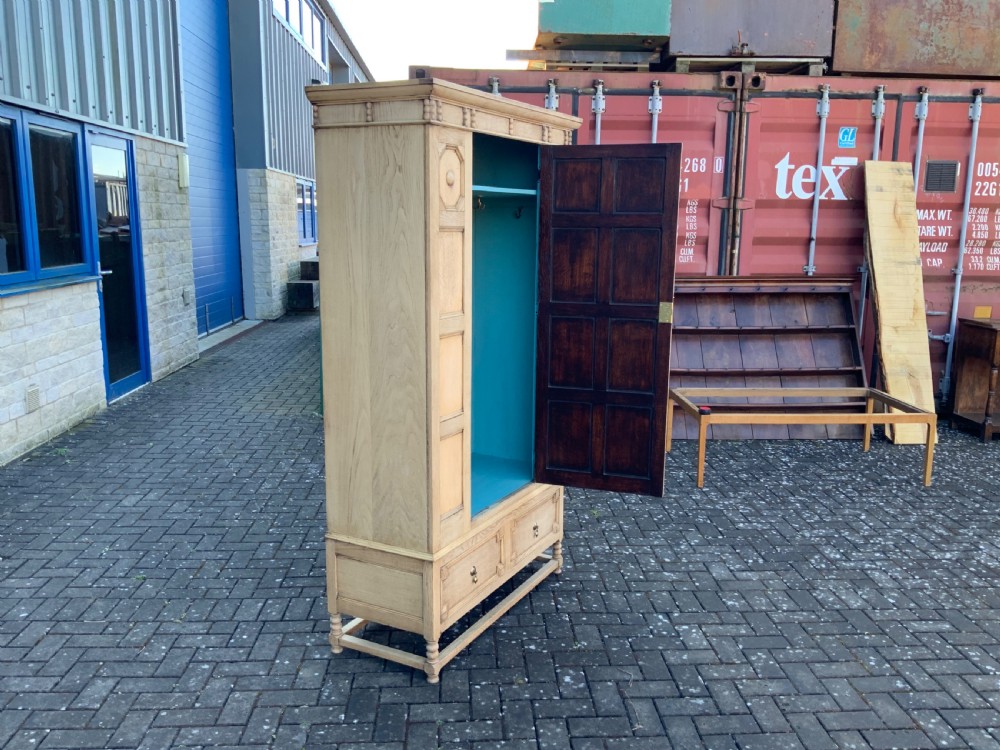 A light oak double wardrobe featuring geometric panelled doors, octagonal raised bosses, two base drawers, and turned legs. View XIII