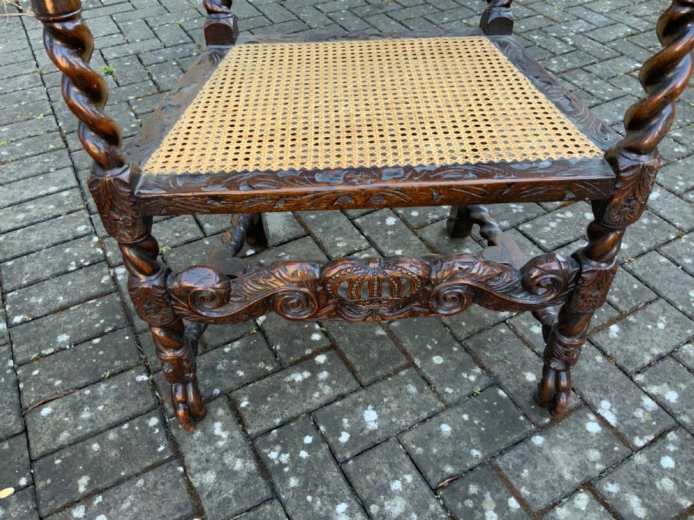 A pair of dark carved oak armchairs featuring high cane backs with carved crown crests, barley twist uprights, curved armrests, and floral upholstered seats. View XI