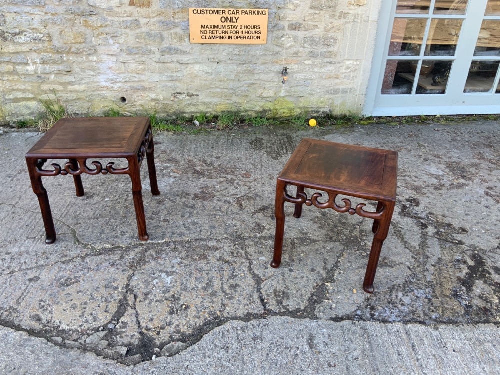 A pair of low square dark brown hardwood side tables featuring carved openwork scroll aprons and shaped legs. View VI