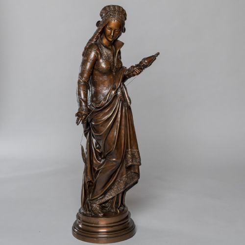 fig 2. A 19th-century dark patinated bronze sculpture depicting a woman in detailed historical attire holding a distaff and thread, standing on a circular moulded base.