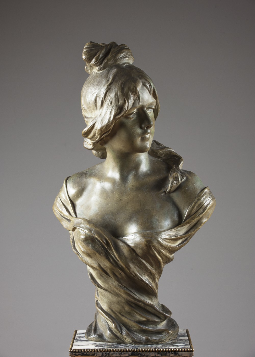 A late 19th-century Art Nouveau terracotta bust depicting a woman with draped clothing and an updo hairstyle, finished in a bronze patina and set on a marble base.