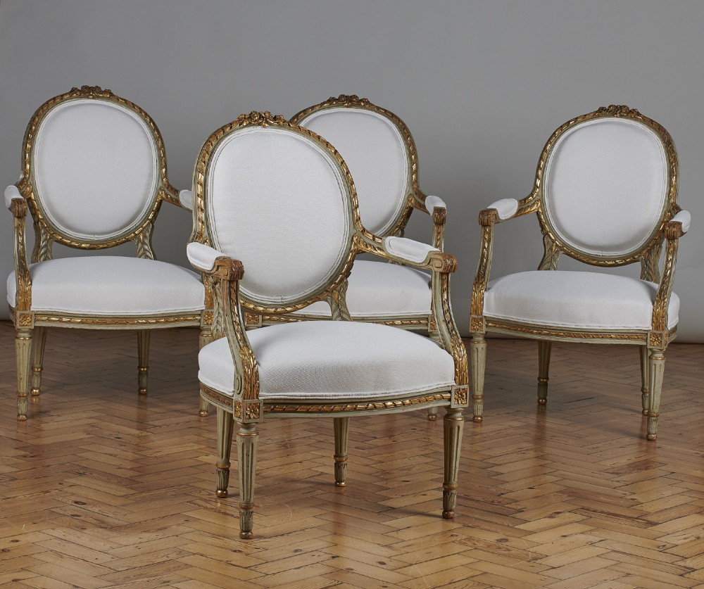 Set Of Four French Louis XVI Style Painted And Gilt Armchairs.