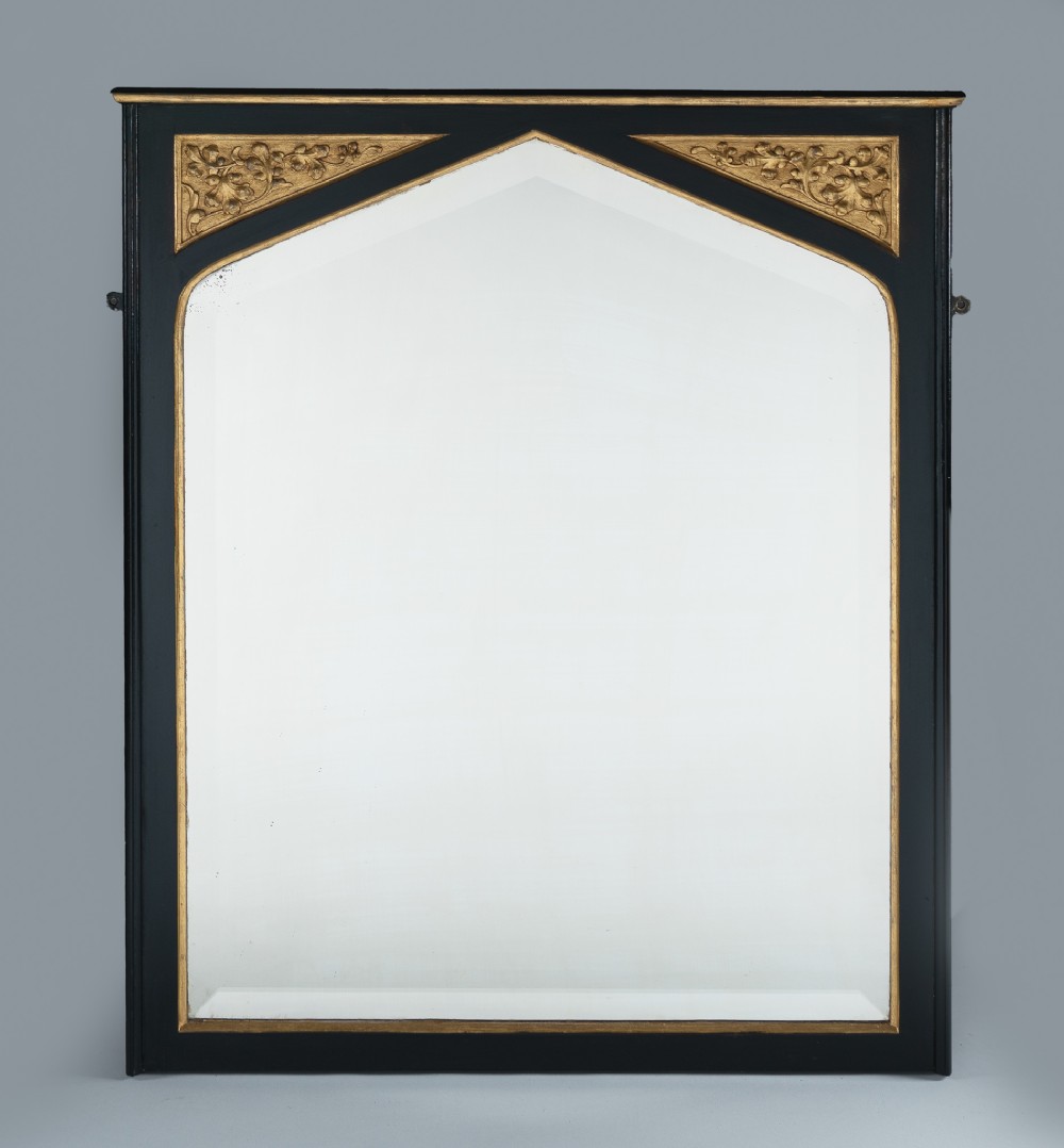 A Victorian ebonised and gilt overmantel mirror featuring a pointed gothic arch frame, carved gold foliage spandrels, and a bevelled mirror plate.